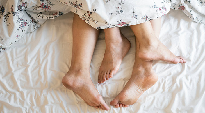 unos pies de una pareja en la cama